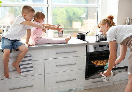 Young mother and kids tasting biscuits in kitchen